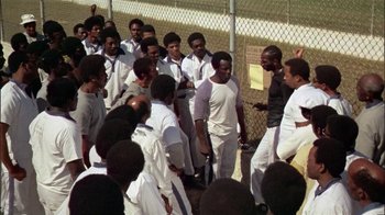 Movie still from “The Longest Yard” (1974), directed by Robert Aldrich – A group of men standing next to each other on top of a field; Wide shot, High angle