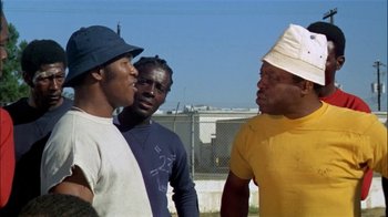 Movie still from “The Longest Yard” (1974), directed by Robert Aldrich – A group of men standing next to each other on top of a field; Medium shot, Low angle
