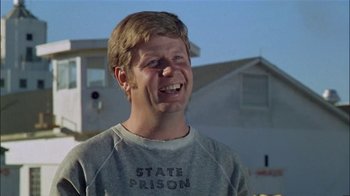 Movie still from “The Longest Yard” (1974), directed by Robert Aldrich – A man in a state prison sweatshirt laughing; Close Up shot, Low angle