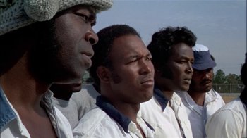 Movie still from “The Longest Yard” (1974), directed by Robert Aldrich – A group of men standing next to each other; Close Up shot, Low angle