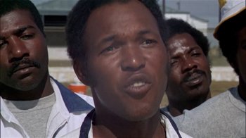 Movie still from “The Longest Yard” (1974), directed by Robert Aldrich – A man's face in front of another man; Close Up shot, Low angle