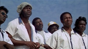 Movie still from “The Longest Yard” (1974), directed by Robert Aldrich – A group of men standing next to each other in white shirts; Close Up shot, Low angle