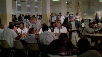 Movie still from “The Longest Yard” (1974), directed by Robert Aldrich – A group of people sitting at tables eating food; Wide shot, High angle