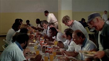 Movie still from “The Longest Yard” (1974), directed by Robert Aldrich – A group of people sitting at a table eating food; Wide shot, High angle