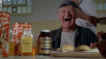 Movie still from “The Longest Yard” (1974), directed by Robert Aldrich – An older man sitting at a table with a sandwich; Close Up shot, Low angle