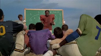Movie still from “The Longest Yard” (1974), directed by Robert Aldrich – A group of people sitting around a chalkboard; Wide shot, High angle