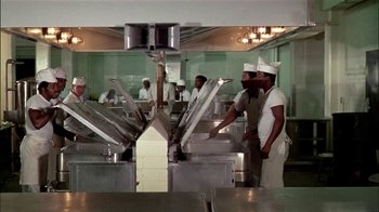 Movie still from “The Longest Yard” (1974), directed by Robert Aldrich – A group of men standing in a kitchen preparing food; Wide shot, Low angle