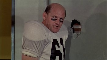 Movie still from “The Longest Yard” (1974), directed by Robert Aldrich – A football player with a number on his face; Medium shot, Low angle