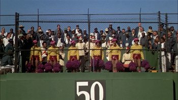 Movie still from “The Longest Yard” (1974), directed by Robert Aldrich – A group of people standing in front of a fence; Wide shot, High angle