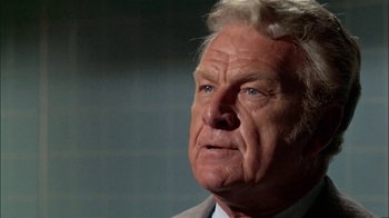 Movie still from “The Longest Yard” (1974), directed by Robert Aldrich – An older man in a gray suit looking to his left; Close Up shot, Low angle