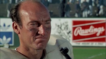Movie still from “The Longest Yard” (1974), directed by Robert Aldrich – A man with a shaved head and a cigarette in his mouth; Close Up shot, Low angle