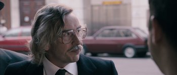 Movie still from “The Look of Love” (2013), directed by Michael Winterbottom – An older man wearing glasses and a suit; Close Up shot, Over the shoulder angle