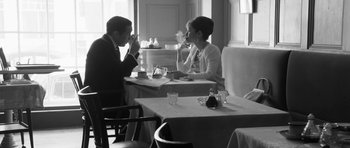 Movie still from “The Look of Love” (2013), directed by Michael Winterbottom – A man and a woman sitting at a table in a restaurant; Medium shot, Over the shoulder angle