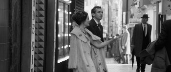 Movie still from “The Look of Love” (2013), directed by Michael Winterbottom – A man and a woman standing next to each other on the sidewalk; Medium shot, Over the shoulder angle