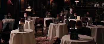 Movie still from “The Look of Love” (2013), directed by Michael Winterbottom – A man in a suit sitting at a table in a restaurant; Wide shot, High angle