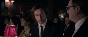 Movie still from “The Look of Love” (2013), directed by Michael Winterbottom – A man wearing a suit and tie holding a glass of wine; Close Up shot, Over the shoulder angle