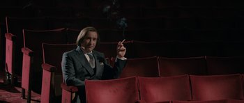 Movie still from “The Look of Love” (2013), directed by Michael Winterbottom – A man in a suit and tie smoking a cigarette; Medium shot, Low angle