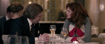 Movie still from “The Look of Love” (2013), directed by Michael Winterbottom – A man and a woman sitting at a table with wine glasses; Medium shot, Over the shoulder angle