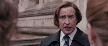 Movie still from “The Look of Love” (2013), directed by Michael Winterbottom – A person wearing a suit and tie; Close Up shot, Over the shoulder angle