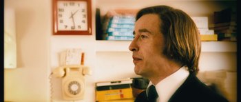 Movie still from “The Look of Love” (2013), directed by Michael Winterbottom – A person wearing a suit and tie; Close Up shot, Over the shoulder angle