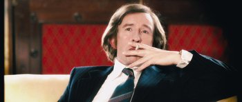 Movie still from “The Look of Love” (2013), directed by Michael Winterbottom – A man in a suit and tie smoking a cigarette; Close Up shot, High angle