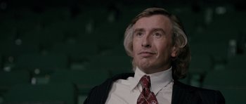 Movie still from “The Look of Love” (2013), directed by Michael Winterbottom – A person wearing a suit and tie; Close Up shot, Over the shoulder angle