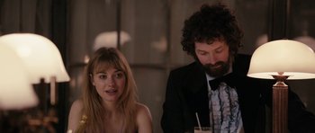 Movie still from “The Look of Love” (2013), directed by Michael Winterbottom – A man and a woman sitting at a dinner table; Medium shot, Over the shoulder angle
