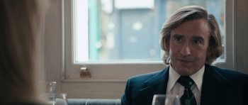 Movie still from “The Look of Love” (2013), directed by Michael Winterbottom – A man sitting in front of a window with a glass of wine; Close Up shot, Over the shoulder angle