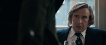 Movie still from “The Look of Love” (2013), directed by Michael Winterbottom – A person sitting at a table with wine glasses; Close Up shot, Over the shoulder angle