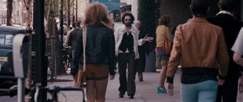 Movie still from “The Look of Love” (2013), directed by Michael Winterbottom – A man walking down the street with a beard; Wide shot, Over the shoulder angle