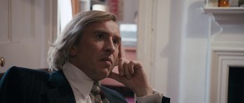 Movie still from “The Look of Love” (2013), directed by Michael Winterbottom – A person wearing a suit and tie; Close Up shot, Over the shoulder angle