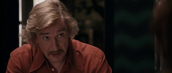 Movie still from “The Look of Love” (2013), directed by Michael Winterbottom – A person wearing a red shirt; Close Up shot, Over the shoulder angle