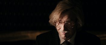 Movie still from “The Look of Love” (2013), directed by Michael Winterbottom – An older man wearing a suit and glasses; Close Up shot, Over the shoulder angle