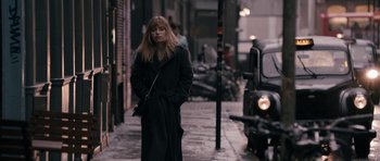 Movie still from “The Look of Love” (2013), directed by Michael Winterbottom – A woman is standing on the sidewalk in the rain; Wide shot, Over the shoulder angle