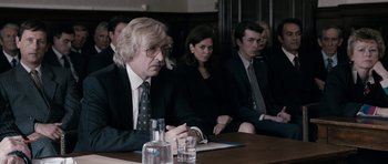 Movie still from “The Look of Love” (2013), directed by Michael Winterbottom – A group of people sitting around a table; Medium shot, Over the shoulder angle