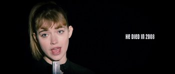 Movie still from “The Look of Love” (2013), directed by Michael Winterbottom – A young woman is holding a microphone up to her mouth; Close Up shot, Over the shoulder angle