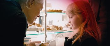 Movie still from “The Look of Love” (2013), directed by Michael Winterbottom – A woman and a child in front of a display case of pastries; Close Up shot, Over the shoulder angle