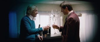 Movie still from “The Look of Love” (2013), directed by Michael Winterbottom – Two people are toasting with wine at a party; Medium shot, Over the shoulder angle