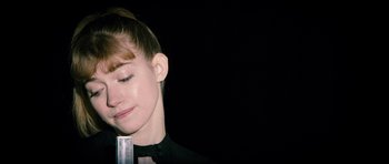 Movie still from “The Look of Love” (2013), directed by Michael Winterbottom – A woman with her eyes closed holding a microphone in her hand; Close Up shot, Over the shoulder angle