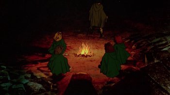 Movie still from “The Lord of the Rings” (1978), directed by Ralph Bakshi – A group of people sitting around a fire pit at night; Wide shot, High angle