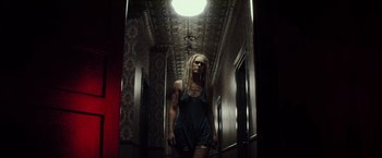 Movie still from “The Lords of Salem” (2012), directed by Rob Zombie – A woman with long blonde dreadlocks walking down a hallway; Wide shot, Low angle