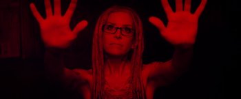 Movie still from “The Lords of Salem” (2012), directed by Rob Zombie – A woman with dreads is holding her hands up in the air; Close Up shot, Low angle