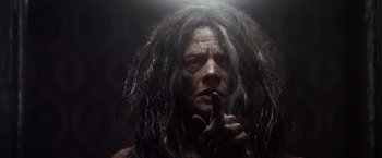 Movie still from “The Lords of Salem” (2012), directed by Rob Zombie – A man with long black hair is holding his finger to his lips; Close Up shot, Low angle