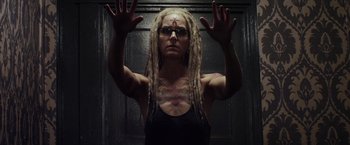 Movie still from “The Lords of Salem” (2012), directed by Rob Zombie – A woman with dreads and glasses holding her hands up in front of a door; Close Up shot, Low angle