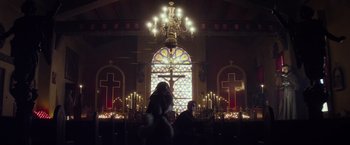 Movie still from “The Lords of Salem” (2012), directed by Rob Zombie – Two people sitting in front of a stained - glass window; Extreme Wide shot, Low angle