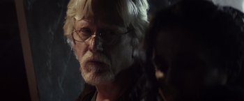 Movie still from “The Lords of Salem” (2012), directed by Rob Zombie – An older man with white hair wearing glasses; Close Up shot, Over the shoulder angle
