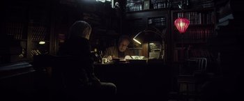 Movie still from “The Lords of Salem” (2012), directed by Rob Zombie – A man sitting at a desk in a dark room with a woman; Medium shot, High angle