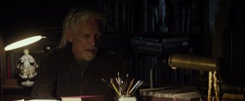 Movie still from “The Lords of Salem” (2012), directed by Rob Zombie – An older man sitting in front of a desk with a bunch of pencils; Medium shot, Low angle