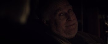 Movie still from “The Lords of Salem” (2012), directed by Rob Zombie – An older man with a goatee is smiling for the camera; Close Up shot, Over the shoulder angle