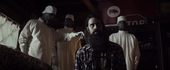 Movie still from “The Lords of Salem” (2012), directed by Rob Zombie – A man with a long beard is getting his hair cut; Medium shot, Low angle